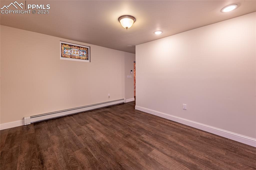 Image 27 of 49: Lower level office with baseboard heating, dark wood-style flooring, and r