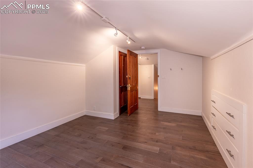 Image 28 of 49: Additional bedroom with vaulted ceiling and dark wood-style floors