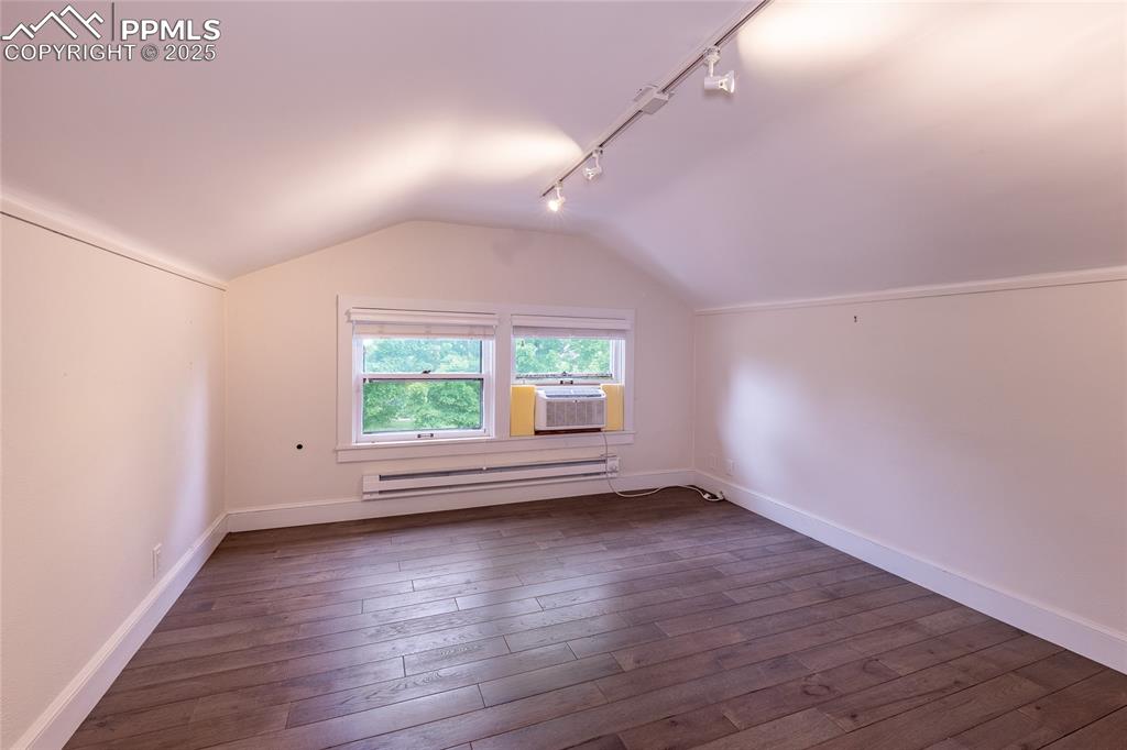 Image 29 of 49: Additional living space featuring vaulted ceiling, dark wood finished floor