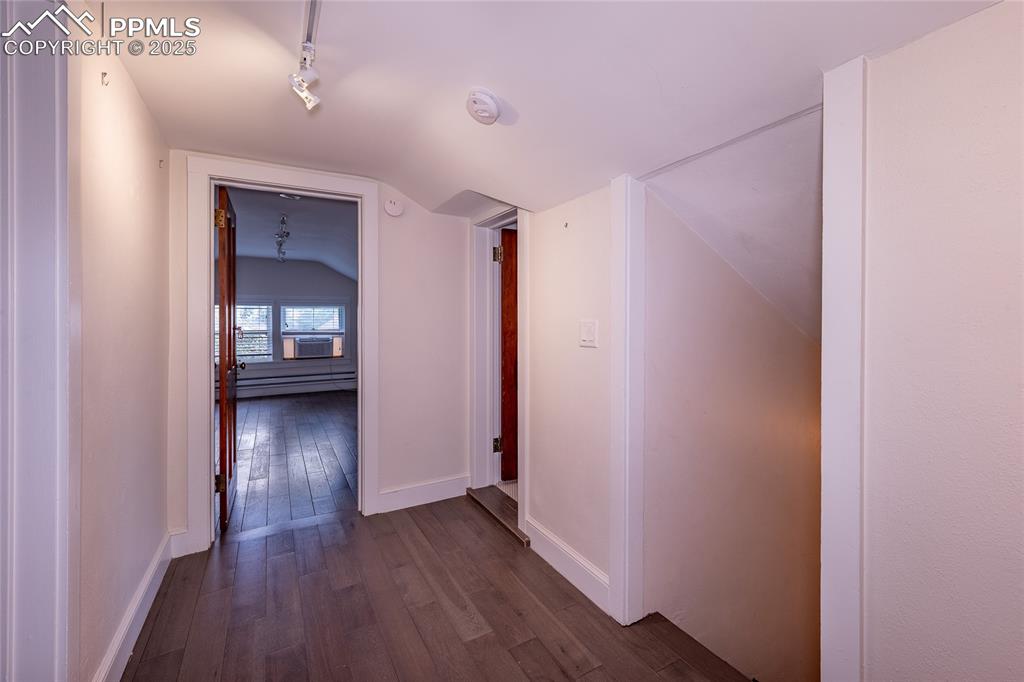 Image 30 of 49: Hall featuring dark wood finished floors, lofted ceiling, a baseboard heati