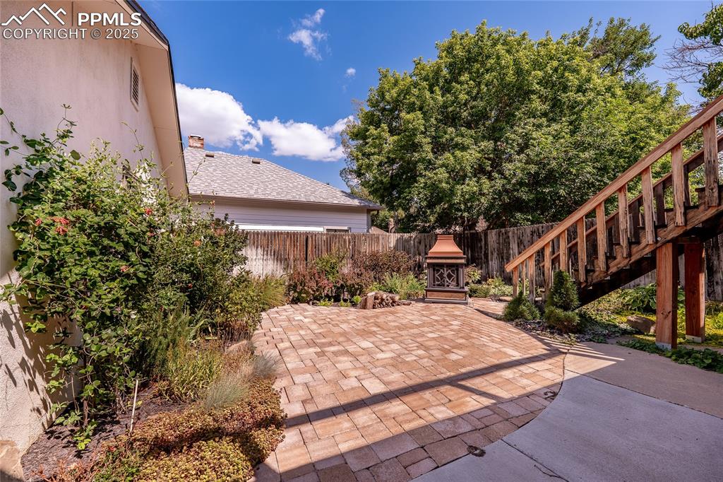 Image 34 of 49: Fenced backyard with a patio and free standing fireplace