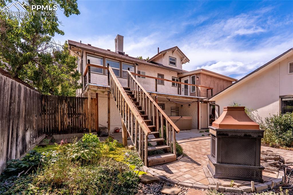 Image 36 of 49: Rear view of property with stairs, a wooden deck, a patio area, fireplace a