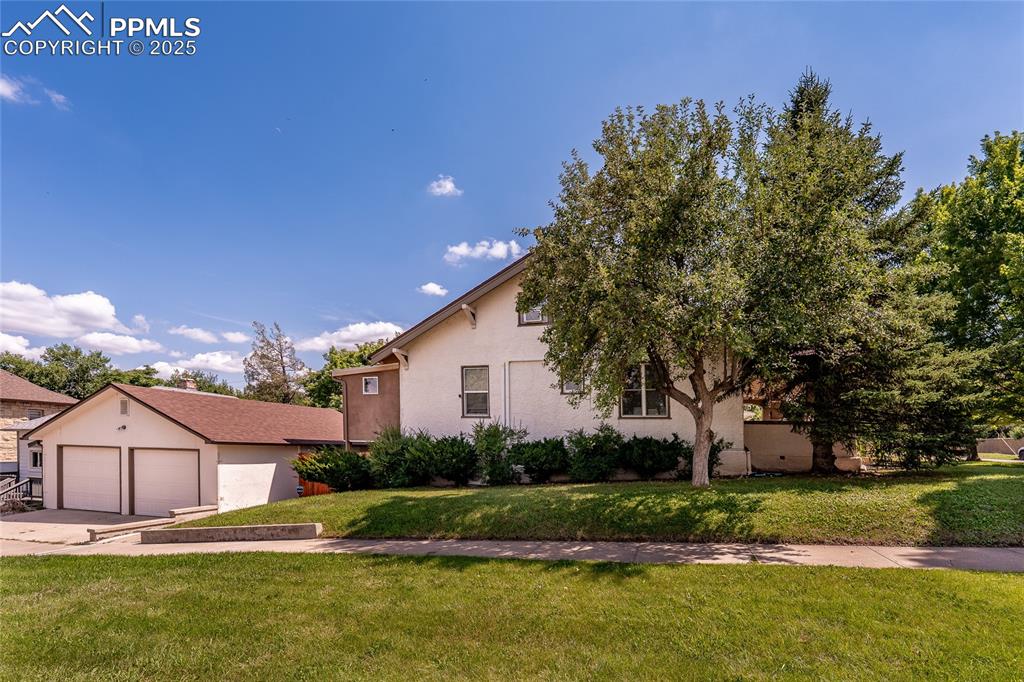Image 40 of 49: View of notrth side of house with a front lawn, a garage, driveway, stucco