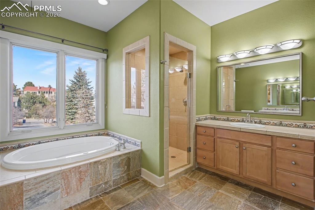 Image 19 of 44: Primary bathroom with natural stone, double vanity, tub, and walk-in shower