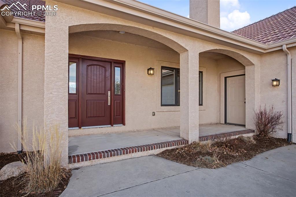 Image 3 of 44: View of front door of home with arched covered porch.