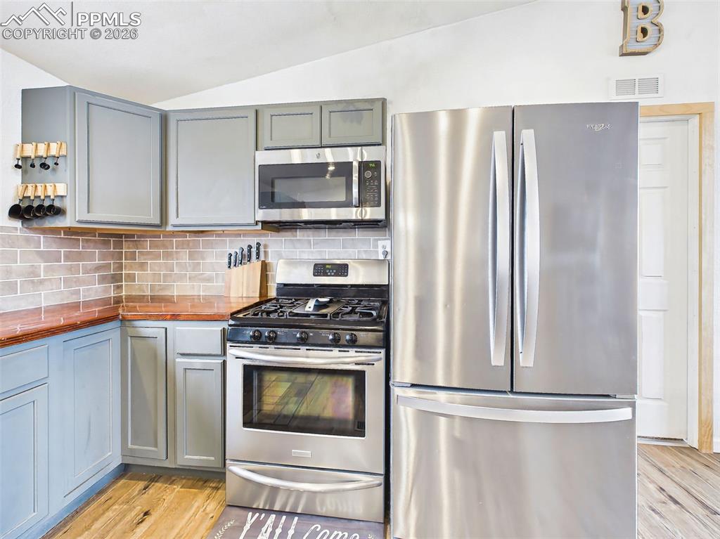 Image 15 of 50: Kitchen – Appliance Detail – Stainless steel refrigerator, range, and built