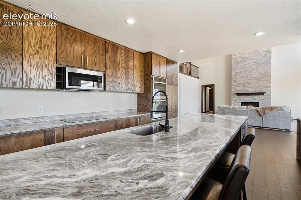 Image 13 of 46: Spacious kitchen island with a dark basin sink and a contemporary gooseneck