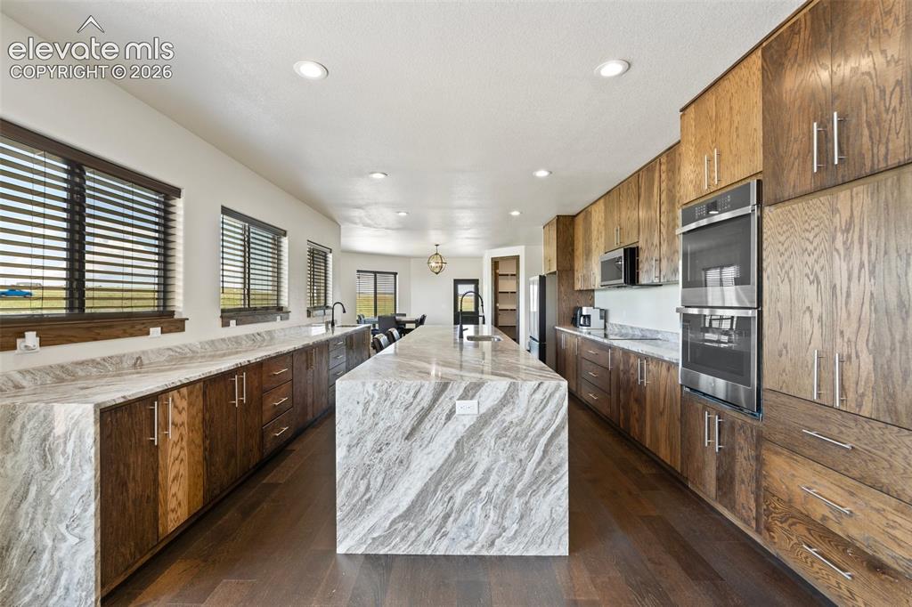 Image 14 of 46: Spacious kitchen featuring a large waterfall island with integrated sink, e
