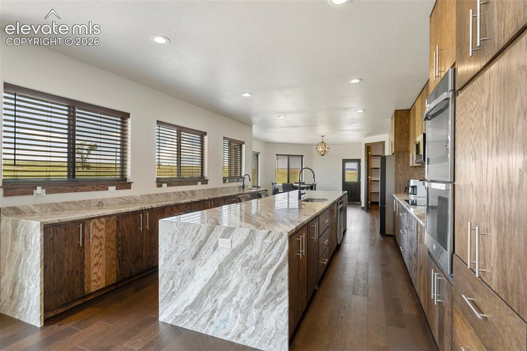 Image 15 of 46: Spacious kitchen featuring a large waterfall island with integrated sink, w