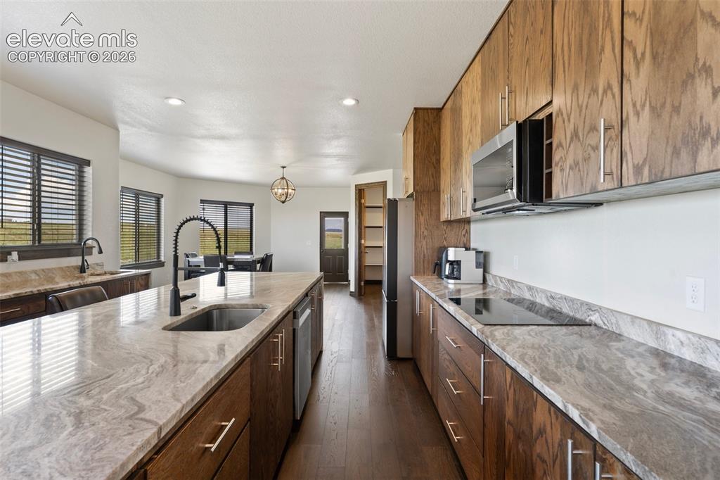 Image 16 of 46: Open-concept kitchen featuring an expansive island with an undermount sink,