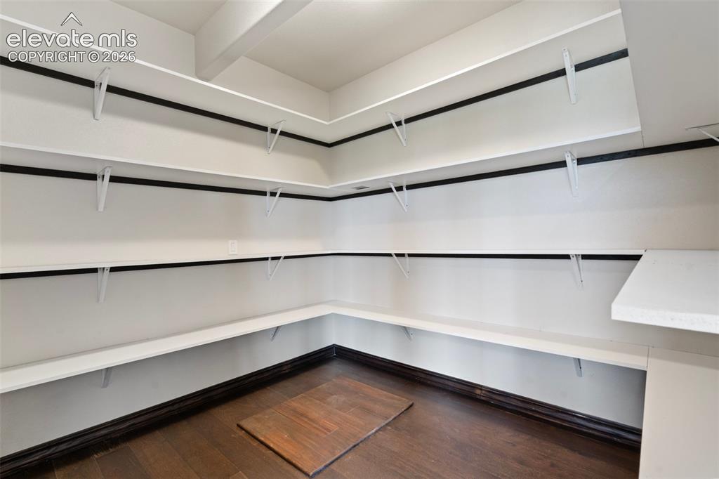 Image 17 of 46: Spacious pantry featuring extensive white shelving, and dark wood-finish fl