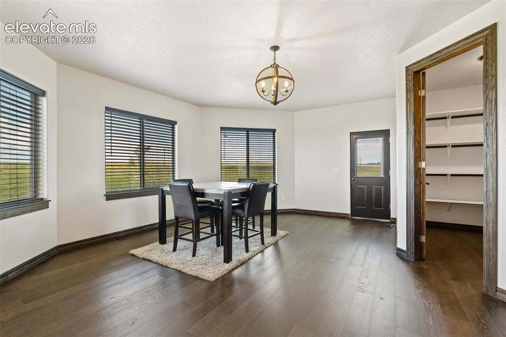 Image 18 of 46: Dining area with dark wood-finish flooring and white walls