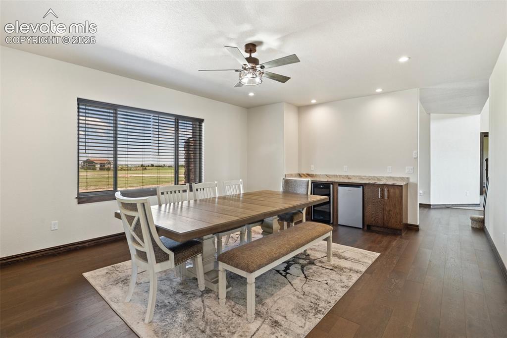 Image 19 of 46: Spacious formal dinning room featuring wood-finish flooring, dry bar with w