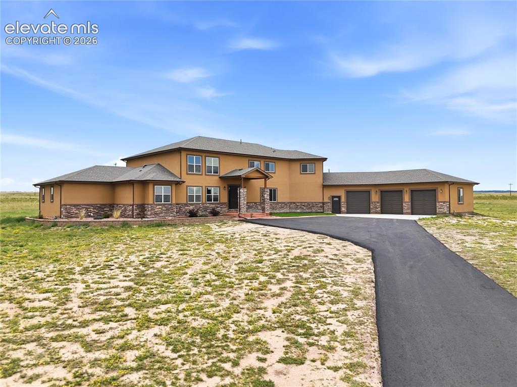 Image 2 of 46: Stucco exterior with stone accenting, multiple windows, covered entry, and