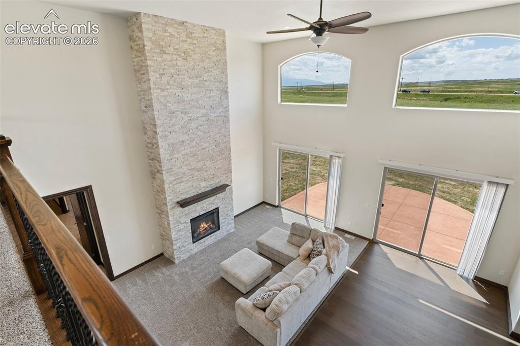 Image 22 of 46: Two-story living area featuring a stacked stone fireplace with wood mantel,