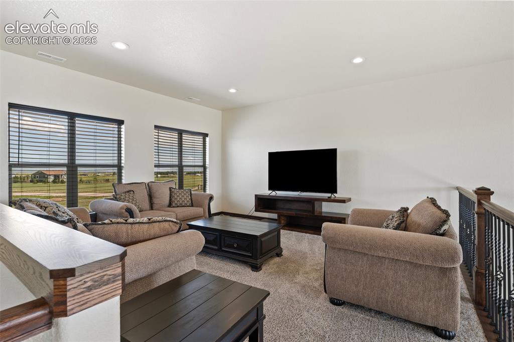 Image 24 of 46: Open-concept loft/living area featuring two large windows with horizontal b