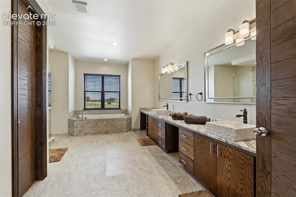 Image 27 of 46: Spacious primary bath featuring a built-in soaking tub, dual vanity with ve