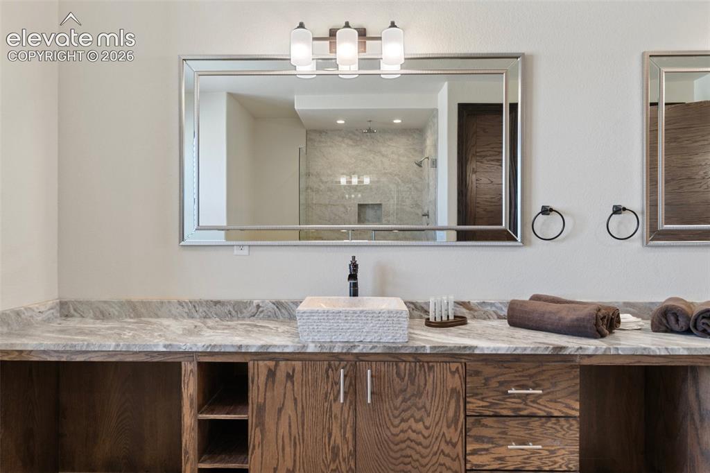 Image 28 of 46: Dual vanity with a stone countertop, featuring a vessel sink and dark wood