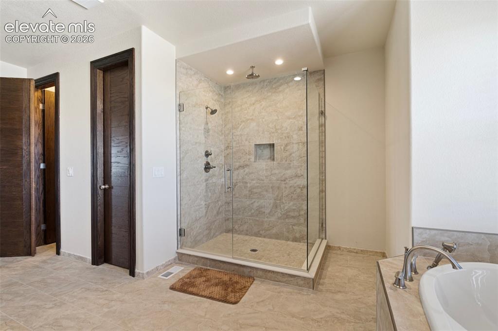 Image 29 of 46: Glass-enclosed shower with a tiled surround and built-in niche, featuring d