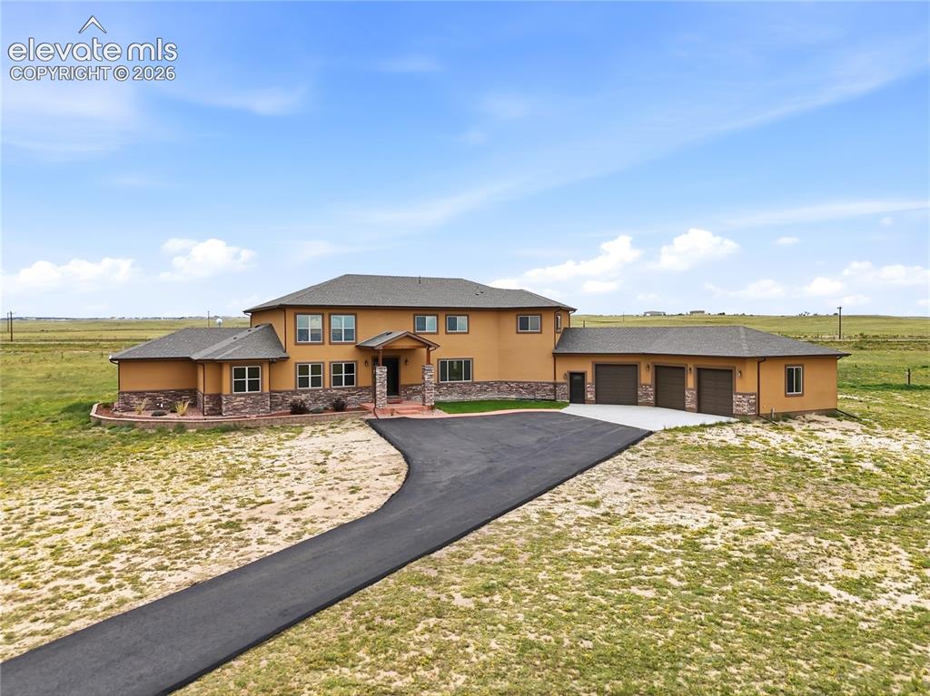 Image 3 of 46: Stucco exterior with stone accents, covered entry, attached three-car garag
