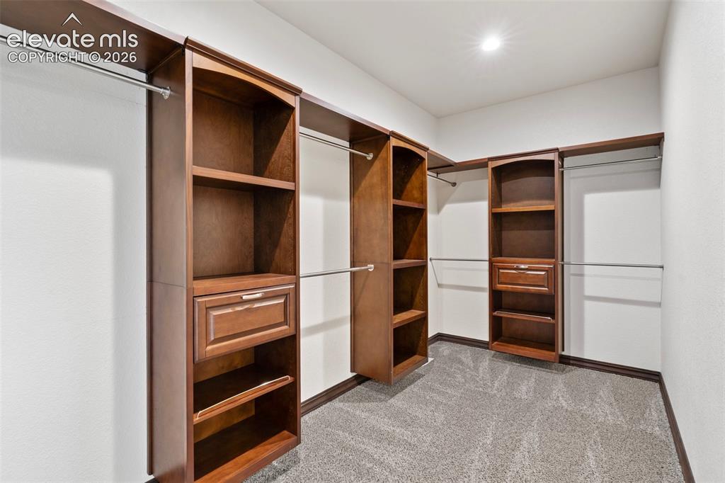 Image 31 of 46: Walk-in closet featuring built-in wood-finish cabinetry, chrome hanging rod