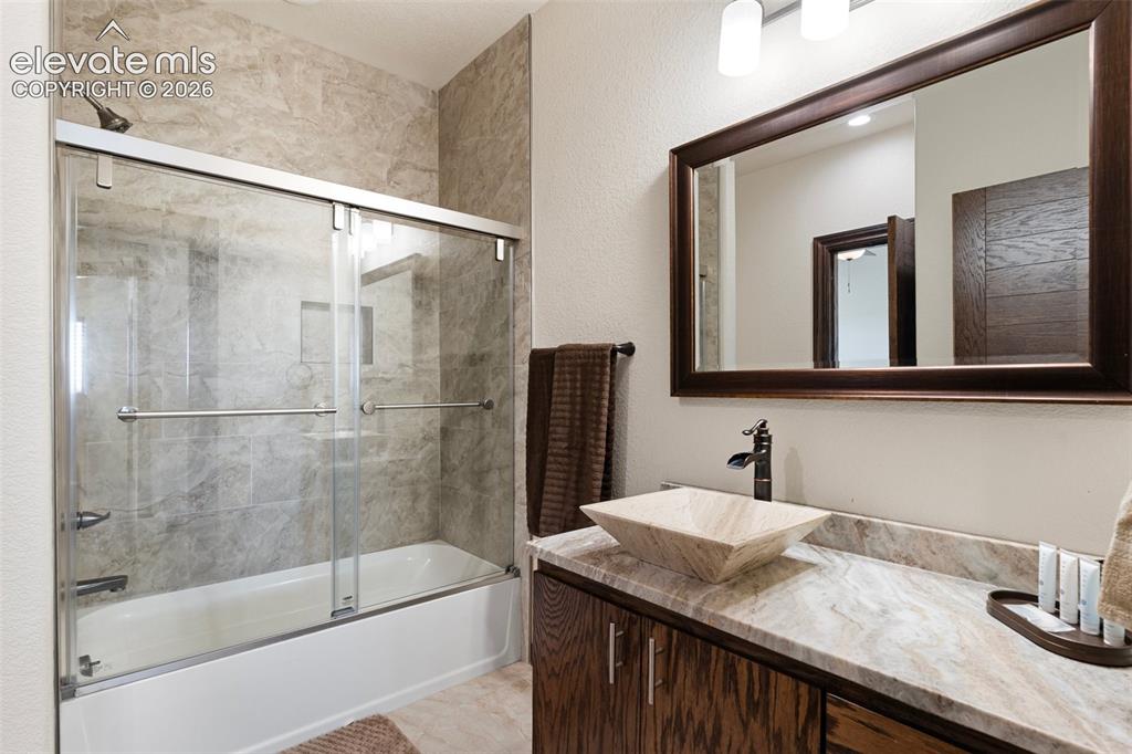 Image 34 of 46: Bathroom featuring a combination tub/shower with sliding glass doors, a van