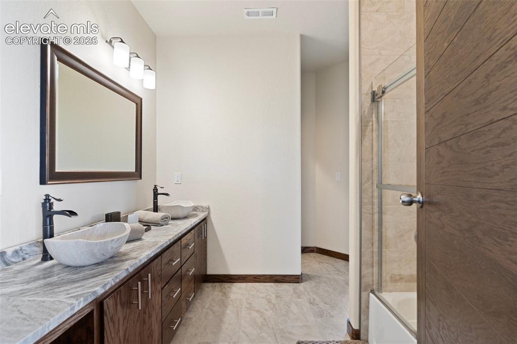 Image 37 of 46: Jack and Jill bath with dual vessel sinks, matte black fixtures set atop a