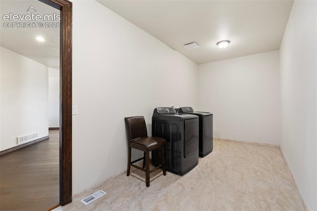 Image 41 of 46: Dedicated laundry area featuring ceramic tile flooring, a recessed ceiling