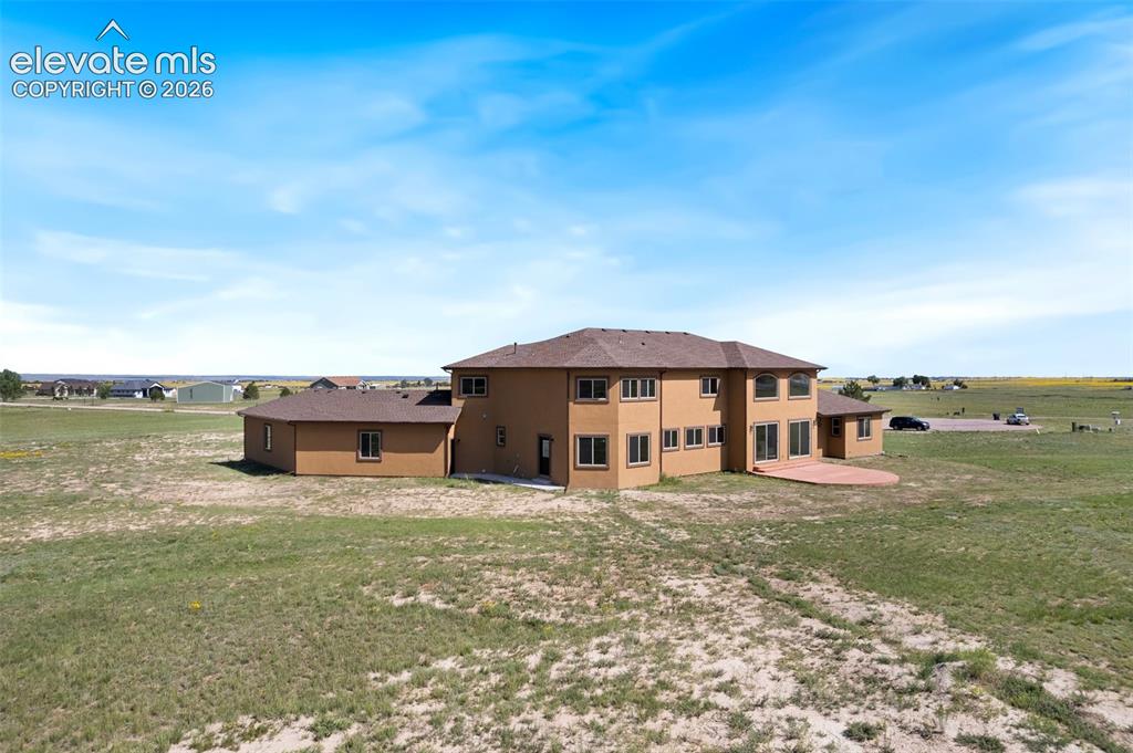 Image 42 of 42: Expansive property featuring a multi-story stucco exterior, a broad brown r