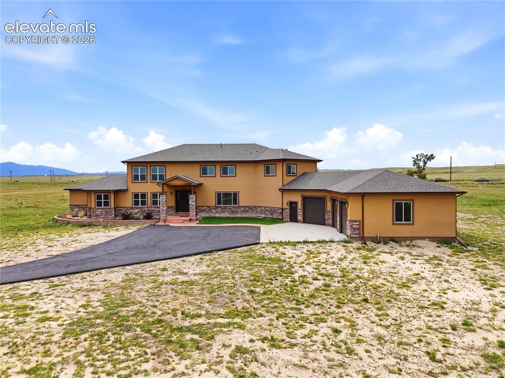 Image 43 of 46: Exterior featuring stucco finish, stone accents, multiple windows, a paved 