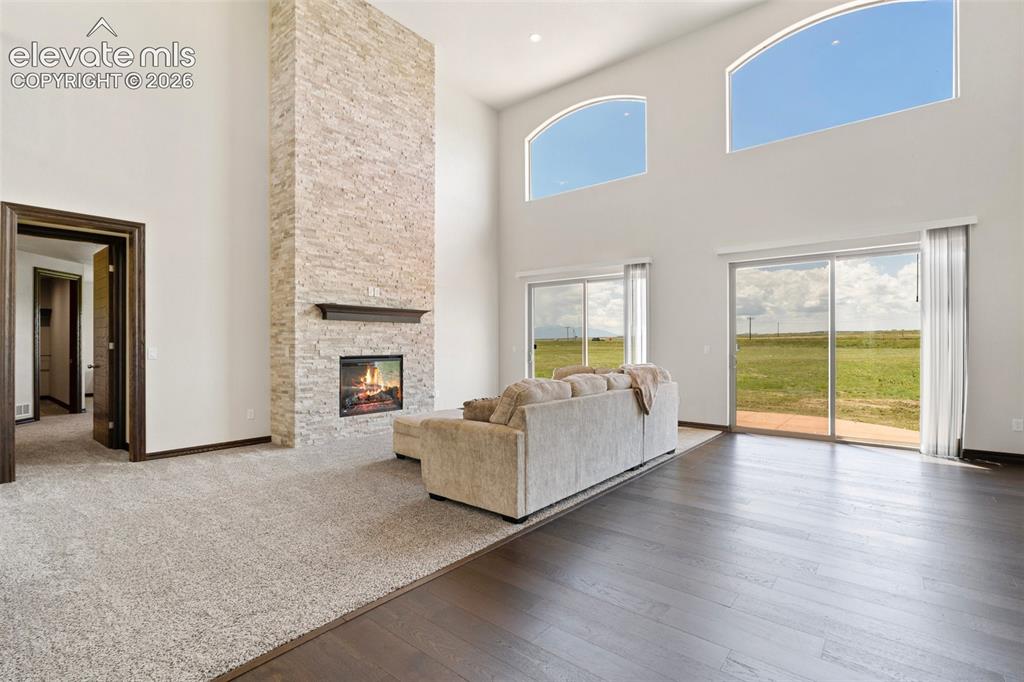 Image 6 of 46: Vaulted living area featuring high arched windows, a stone fireplace, and s