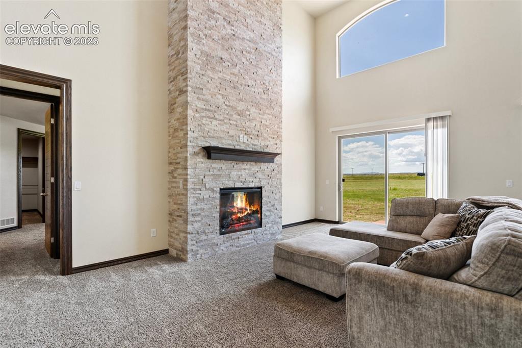 Image 7 of 46: Vaulted living area featuring high arched windows, a stone fireplace, and s