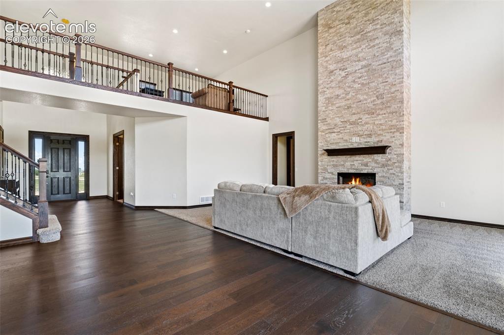 Image 8 of 46: Great room featuring a floor-to-ceiling stone fireplace with a dark wood ma