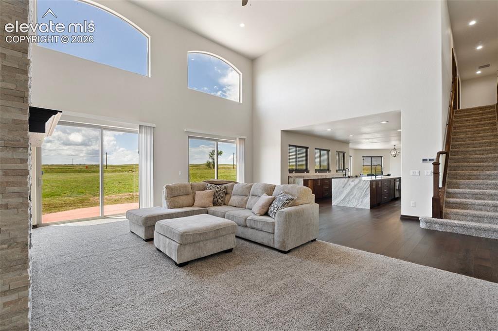 Image 9 of 46: Vaulted living area featuring high arched windows, a stone fireplace, and s