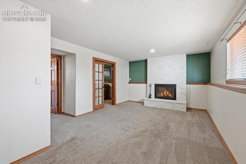 Image 14 of 25: Recessed lighting, wood-trim baseboards, and a fireplace with a stacked sto