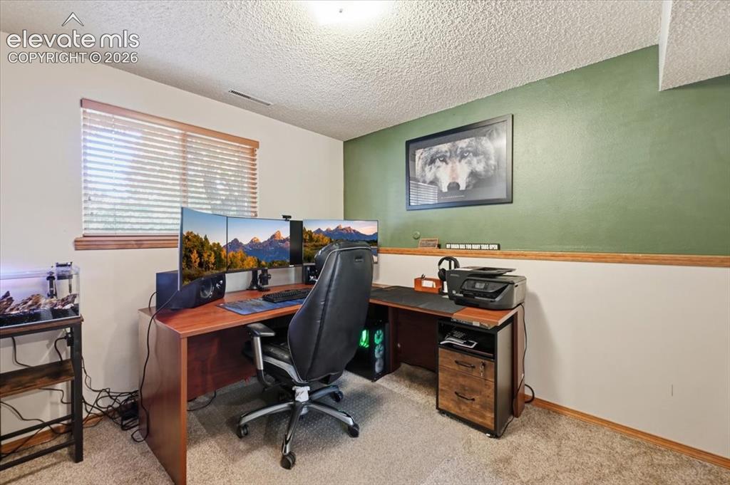Image 16 of 25: Wood-finish desk, wood trim, two-tone wall paint, and textured ceiling