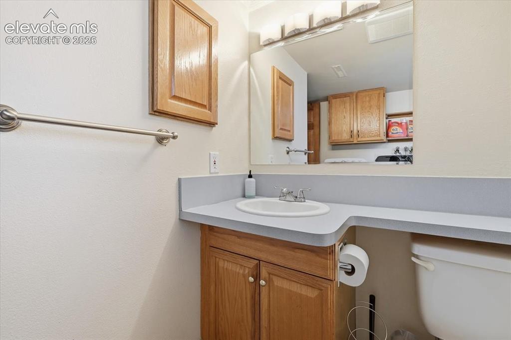 Image 17 of 25: Vanity with an integrated sink, laminate countertop, and wood-finish cabine