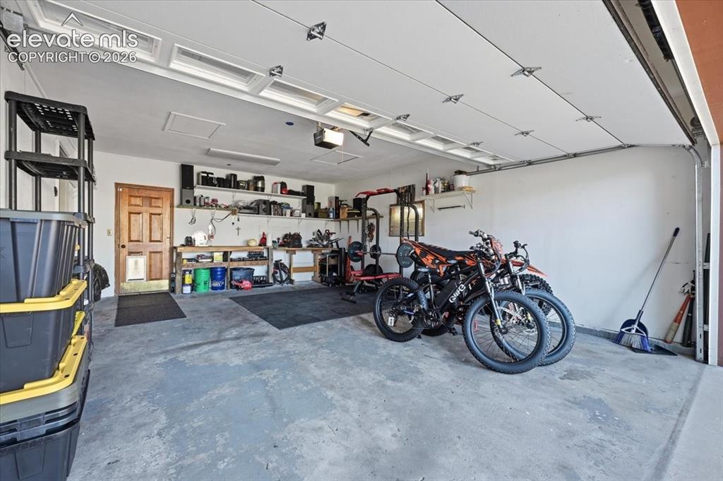 Image 20 of 25: Attached garage featuring a light gray concrete floor, white walls, and a p