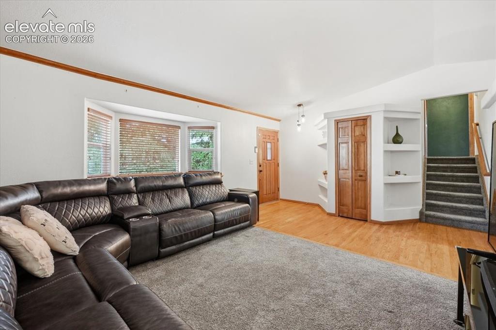 Image 4 of 25: Bay window with blinds, wood-finish flooring, built-in shelving, carpeted s