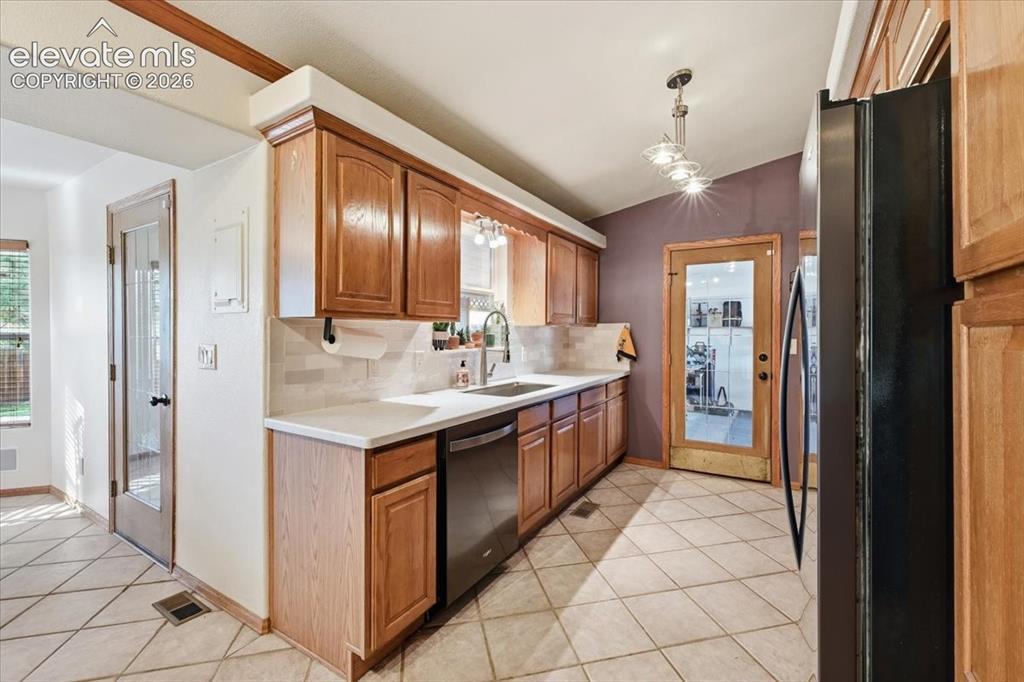 Image 7 of 25: Kitchen featuring wood cabinetry, white countertops, tile backsplash, and t