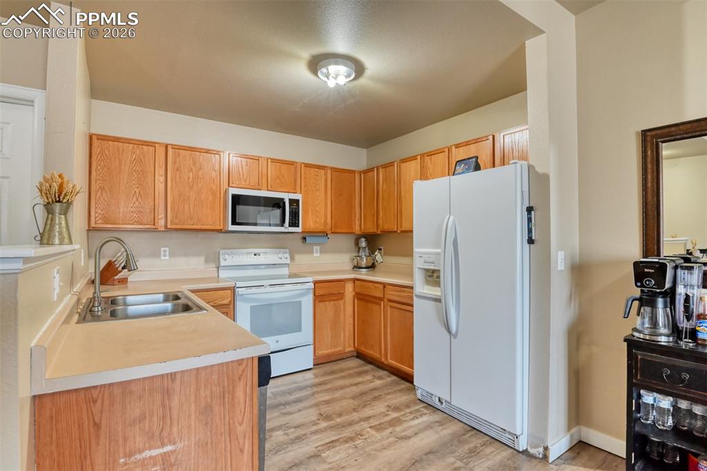 Image 10 of 35: Kitchen featuring white appliances, light countertops, light wood-style flo