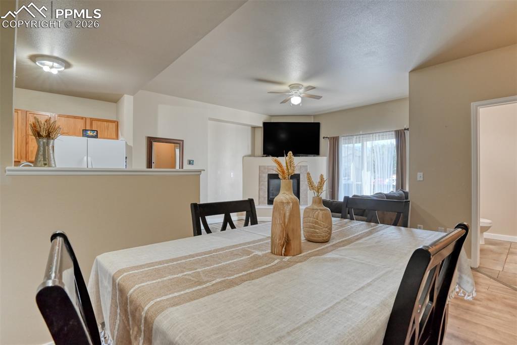 Image 16 of 35: Dining space featuring ceiling fan, a fireplace, and a textured ceiling