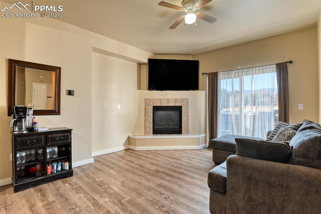 Image 3 of 35: Living room featuring a ceiling fan, light wood-style floors, and a tiled f