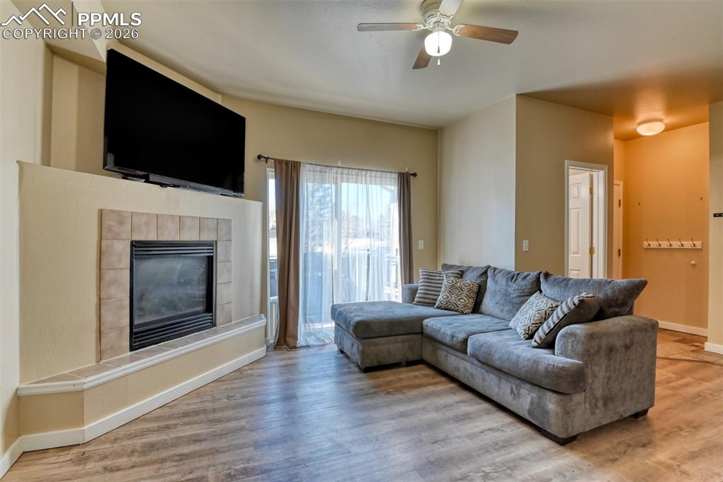 Image 5 of 35: Living area with light wood-style floors, ceiling fan, and a tile fireplace