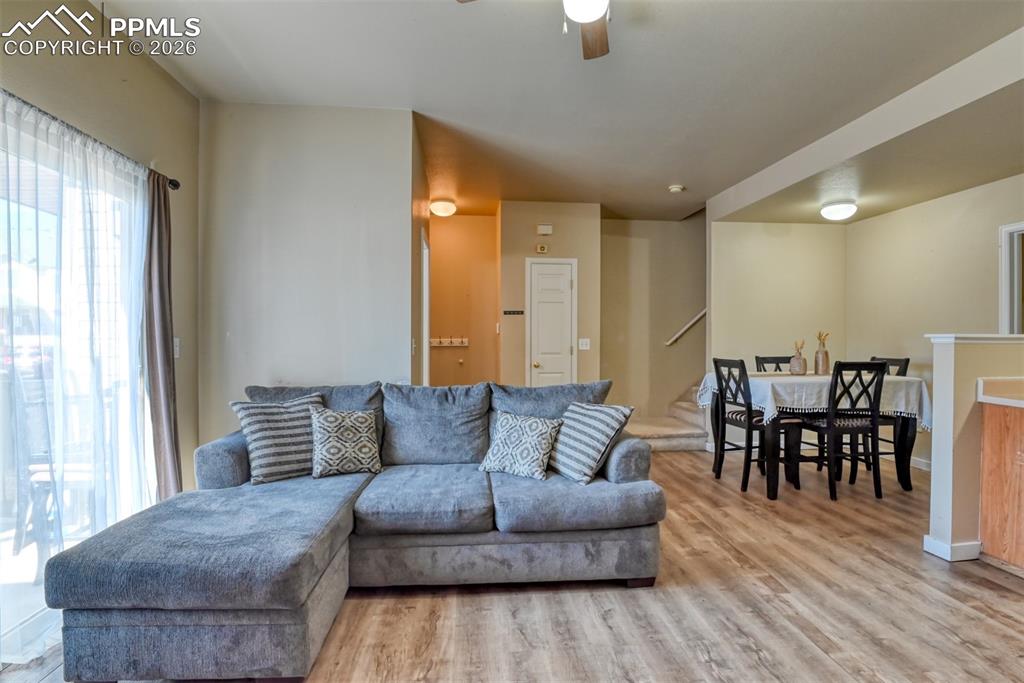 Image 6 of 35: Living room with light wood finished floors and a ceiling fan