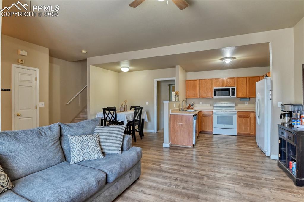 Image 7 of 35: Living room with a ceiling fan and light wood-style floors