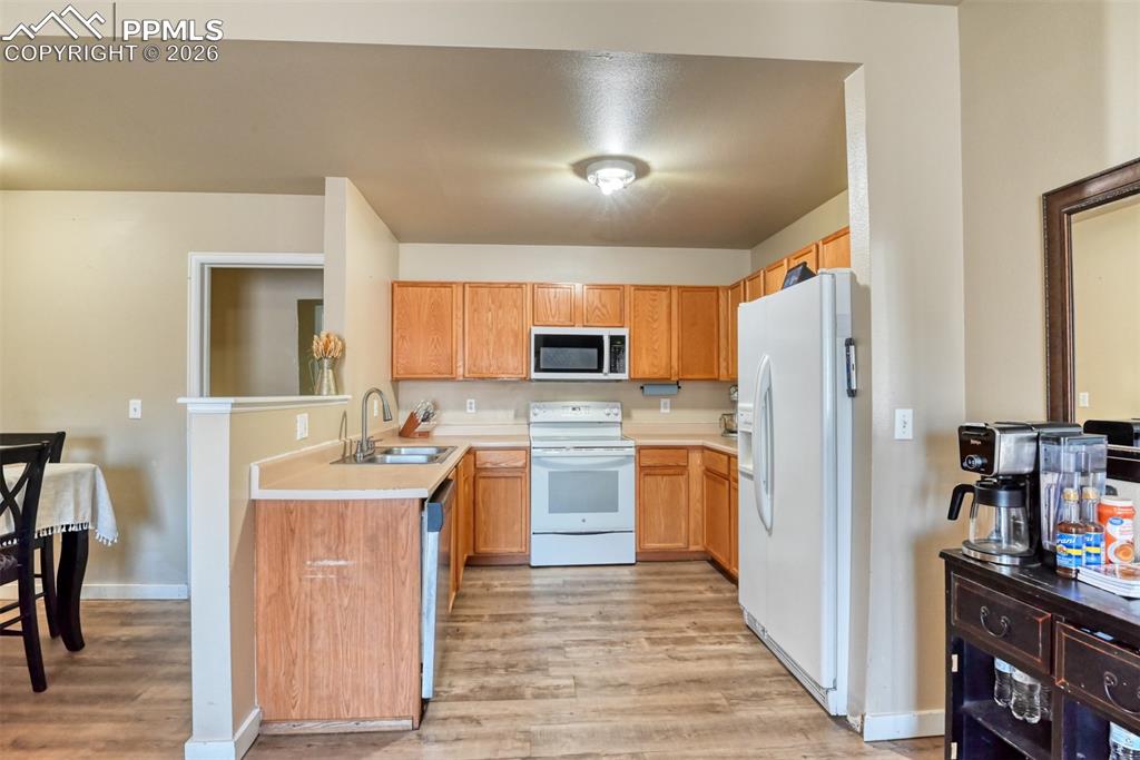 Image 8 of 35: Kitchen featuring light countertops, white appliances, light wood-style flo