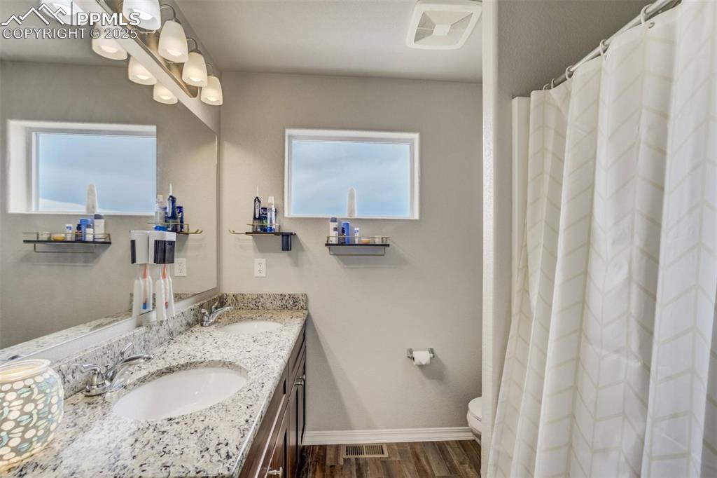 Image 21 of 27: Bathroom featuring double vanity and wood finished floors