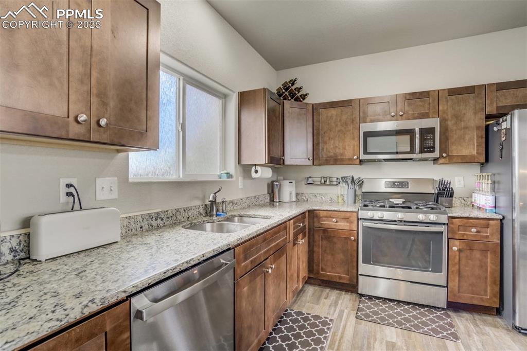 Image 8 of 27: Kitchen featuring appliances with stainless steel finishes, light wood-styl