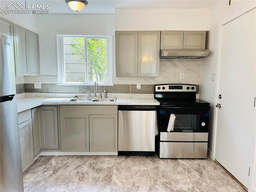 Image 4 of 9: Kitchen featuring appliances with stainless steel finishes, gray cabinetry,